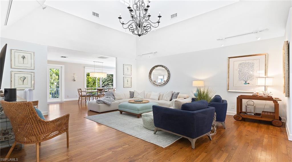 Living area with hardwood / wood-style floors, a high ceiling, and suspended lighting