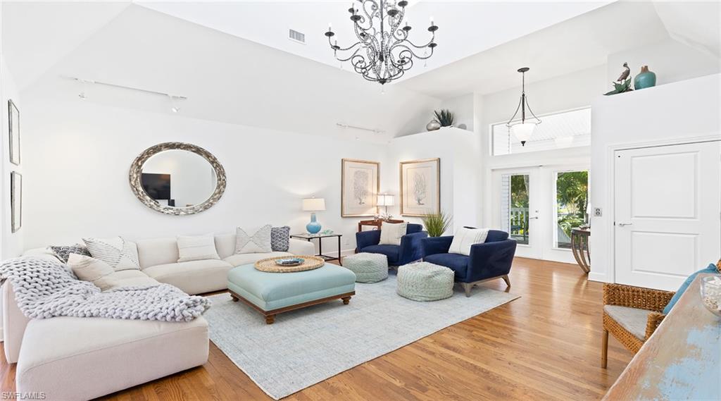 Living area with french doors, light wood-type flooring, lofted ceiling, and suspended lighting