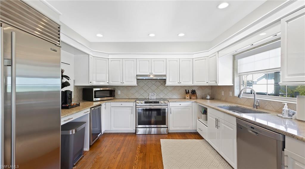 Kitchen featuring stainless steel appliances, white cabinetry, light stone countertops, and recessed lighting