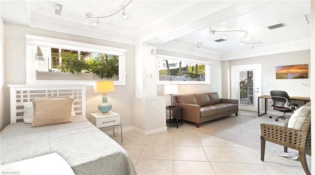 Bedroom featuring an office area, access to exterior, rail lighting, and light tile patterned floors