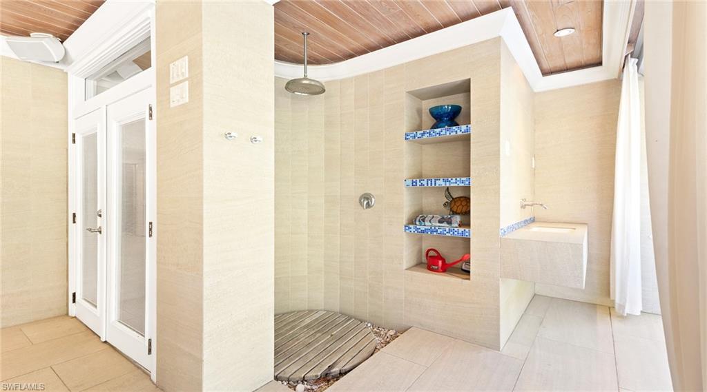 Bathroom featuring a walk in shower, wooden ceiling, built in shelves, light tile patterned floors, and tile walls