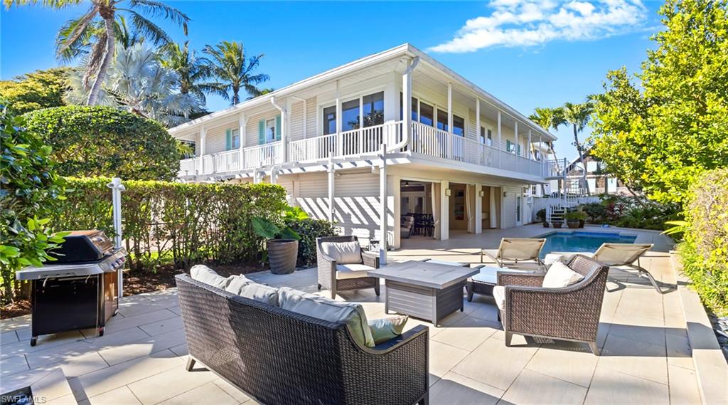 Rear view of property featuring a patio, outdoor lounge area, an outdoor pool, and a balcony