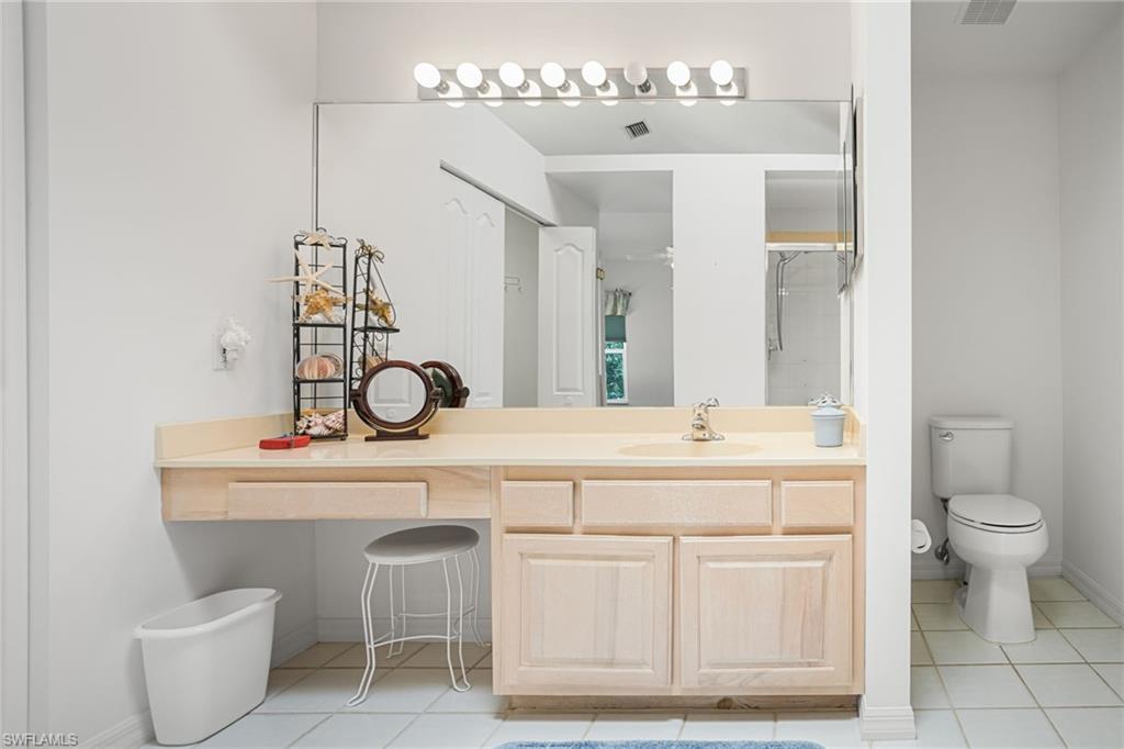 The second-floor primary bathroom has a large, tiled walk-in shower and extra-wide vanity, plus vaulted ceiling with a skylight.