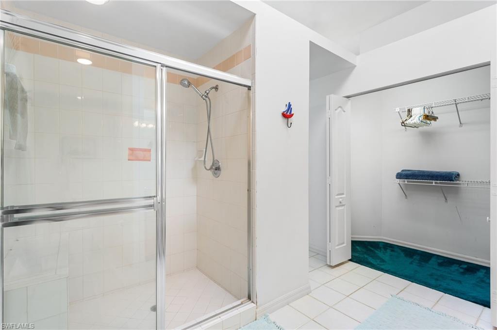 The second-floor primary bathroom has a large, tiled walk-in shower and extra-wide vanity, plus vaulted ceiling with a skylight.