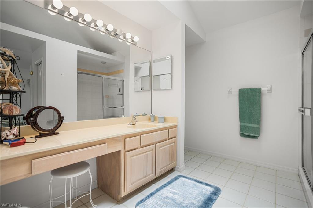 The second-floor primary bathroom has a large, tiled walk-in shower and extra-wide vanity, plus vaulted ceiling with a skylight.