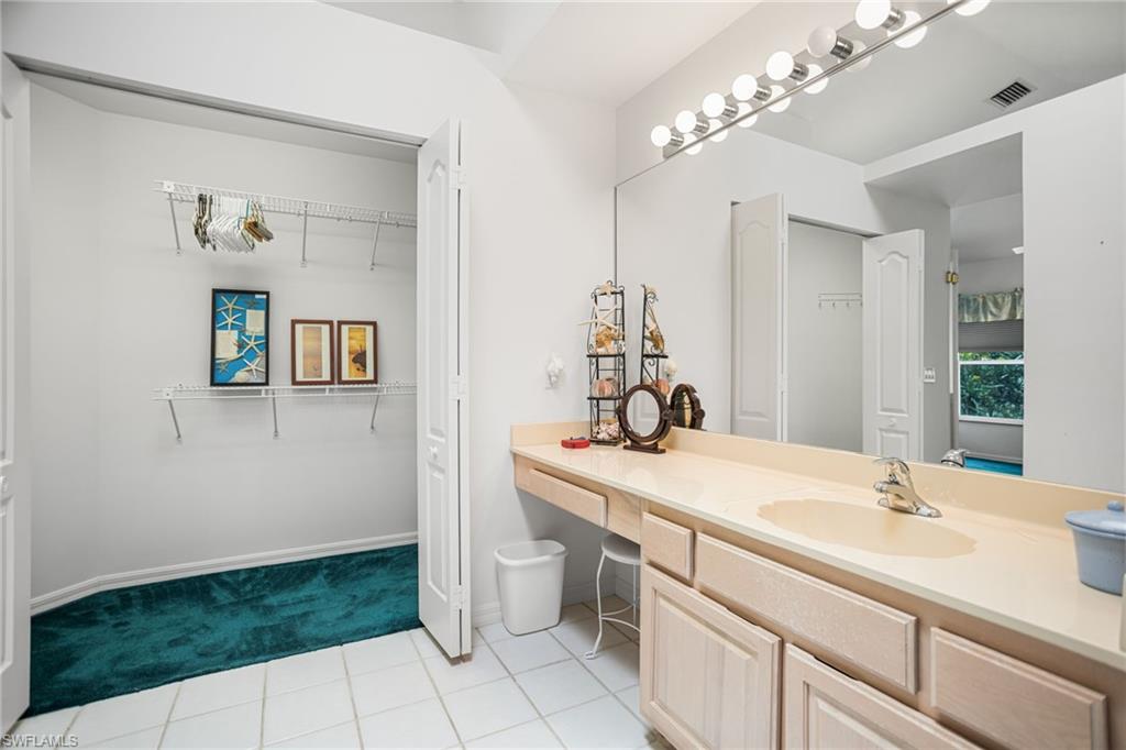 The second-floor primary bathroom has a large, tiled walk-in shower and extra-wide vanity, plus vaulted ceiling with a skylight.