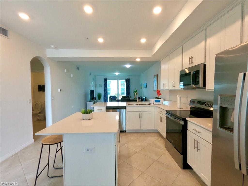 Kitchen with stainless steel appliances, white cabinets, a breakfast bar, recessed lighting, and arched walkways
