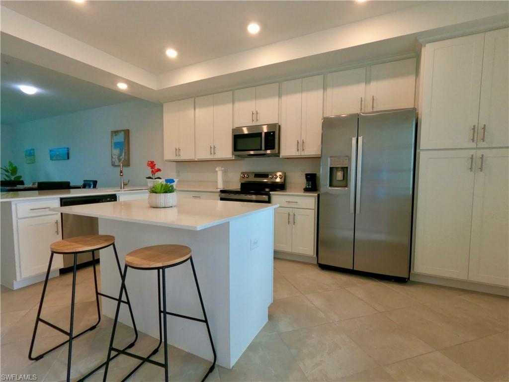 Kitchen with white cabinets, appliances with stainless steel finishes, a breakfast bar, a center island, and recessed lighting