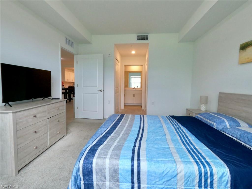 Bedroom with light colored carpet and connected bathroom