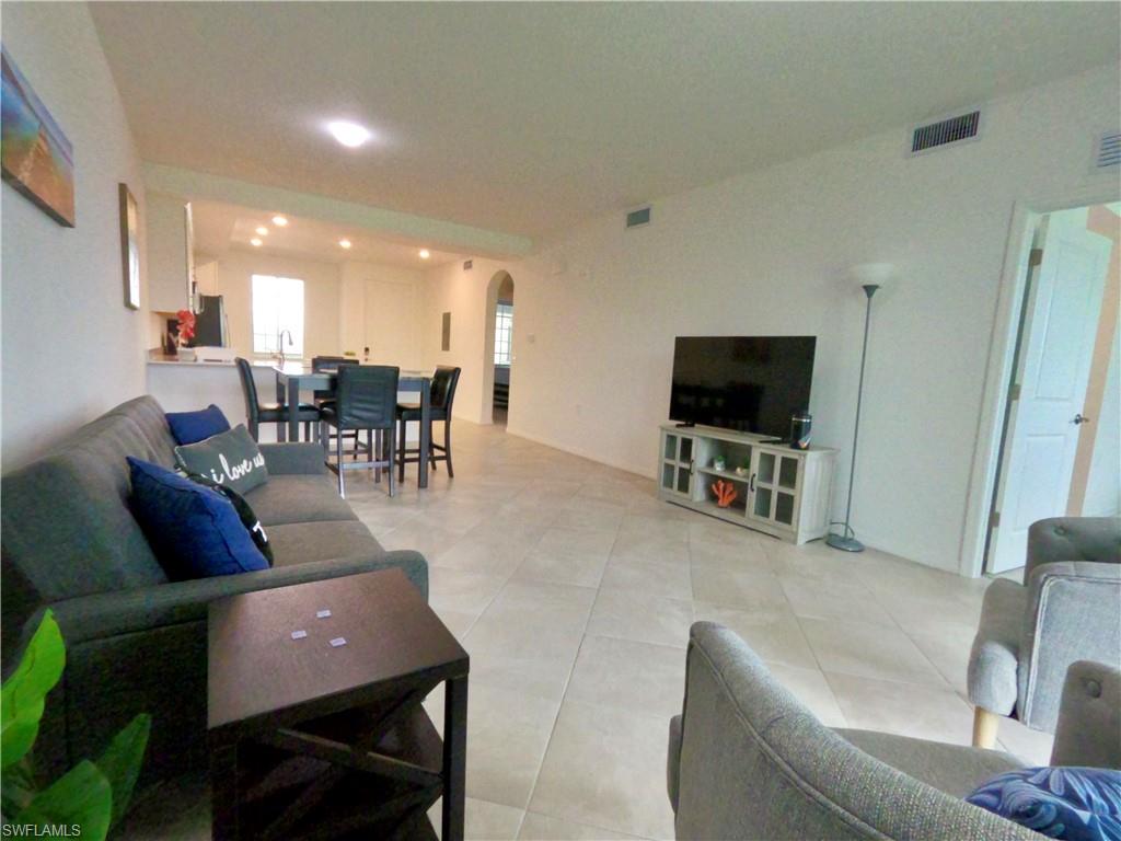 Living room featuring arched walkways, recessed lighting, and light tile patterned floors