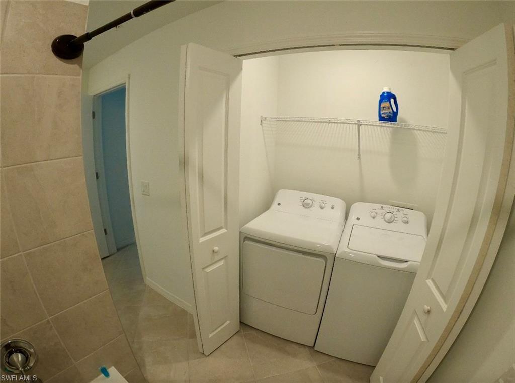 Washroom with light tile patterned floors and washing machine and dryer