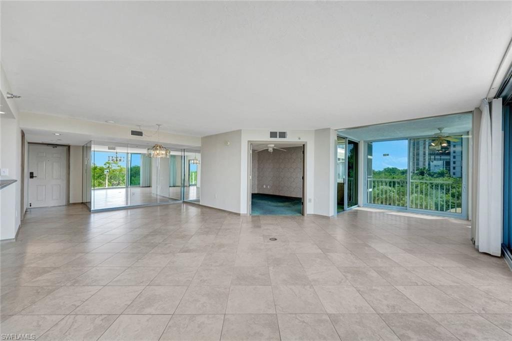 Unfurnished living room featuring ceiling fan and a chandelier