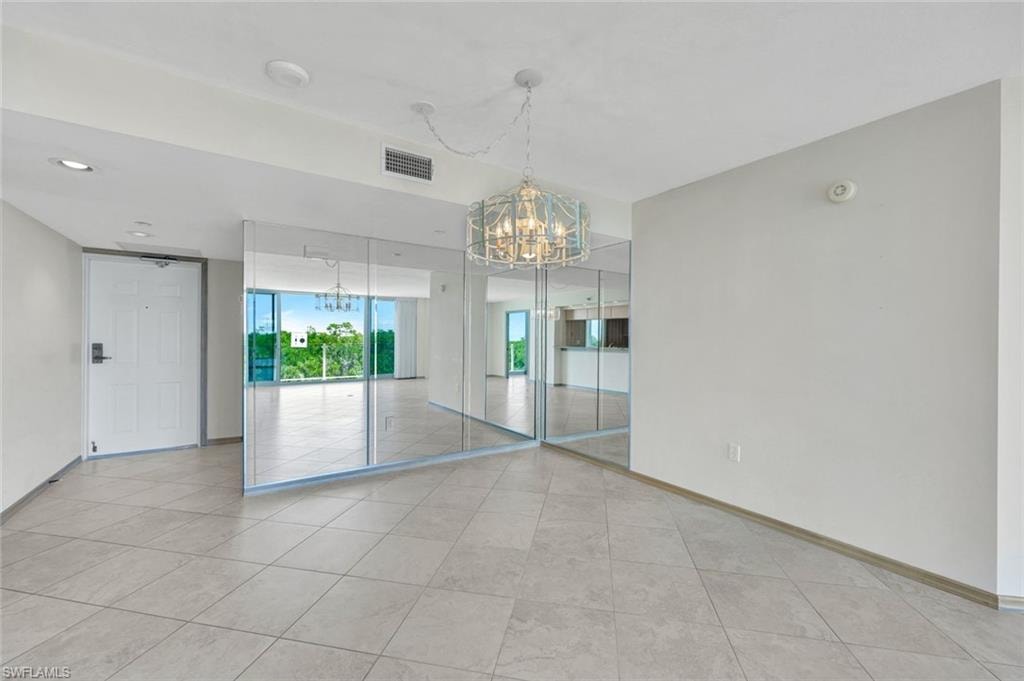 Empty room featuring a chandelier and light tile patterned flooring