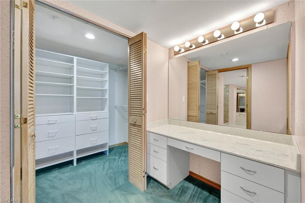Primary Bathroom with vanity, recessed lighting, wallpapered walls, and a walk in closet