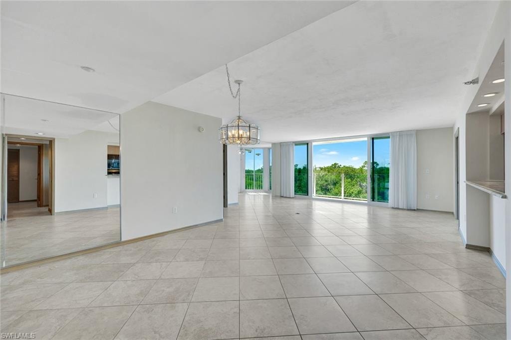 Spare room with floor to ceiling windows, a chandelier, light tile patterned floors, and recessed lighting