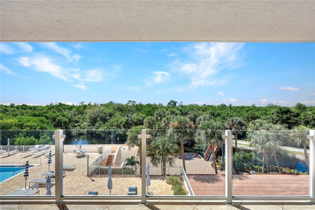 Balcony featuring view of pool area and a forest view
