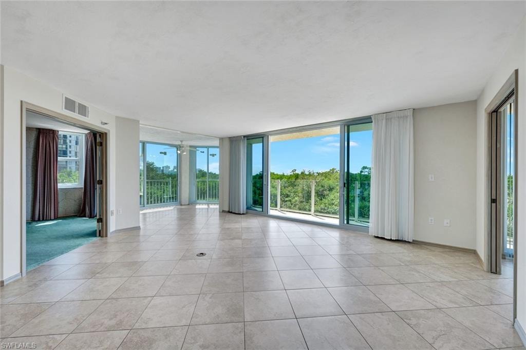Unfurnished room with expansive windows and light tile patterned floors
