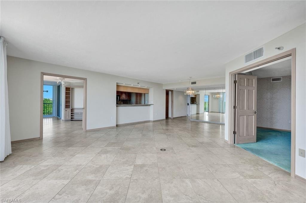 Unfurnished living room with a chandelier and baseboards