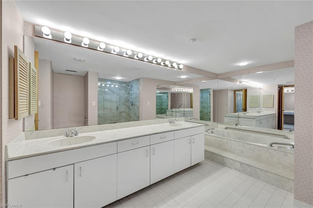 Primary bathroom with a marble finish shower, double vanity, light tile patterned flooring, and a bath