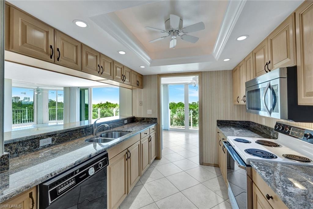 Kitchen with ceiling fan, dark stone countertops, white electric stove, dishwasher, and recessed lighting
