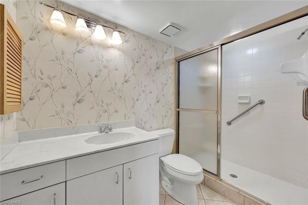 Guest Bathroom featuring wallpapered walls, vanity, a stall shower, and light tile patterned flooring