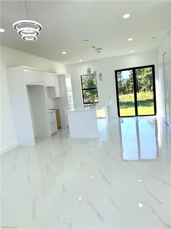 Kitchen with pendant lighting, healthy amount of natural light, appliances with stainless steel finishes, white cabinets, and recessed lighting