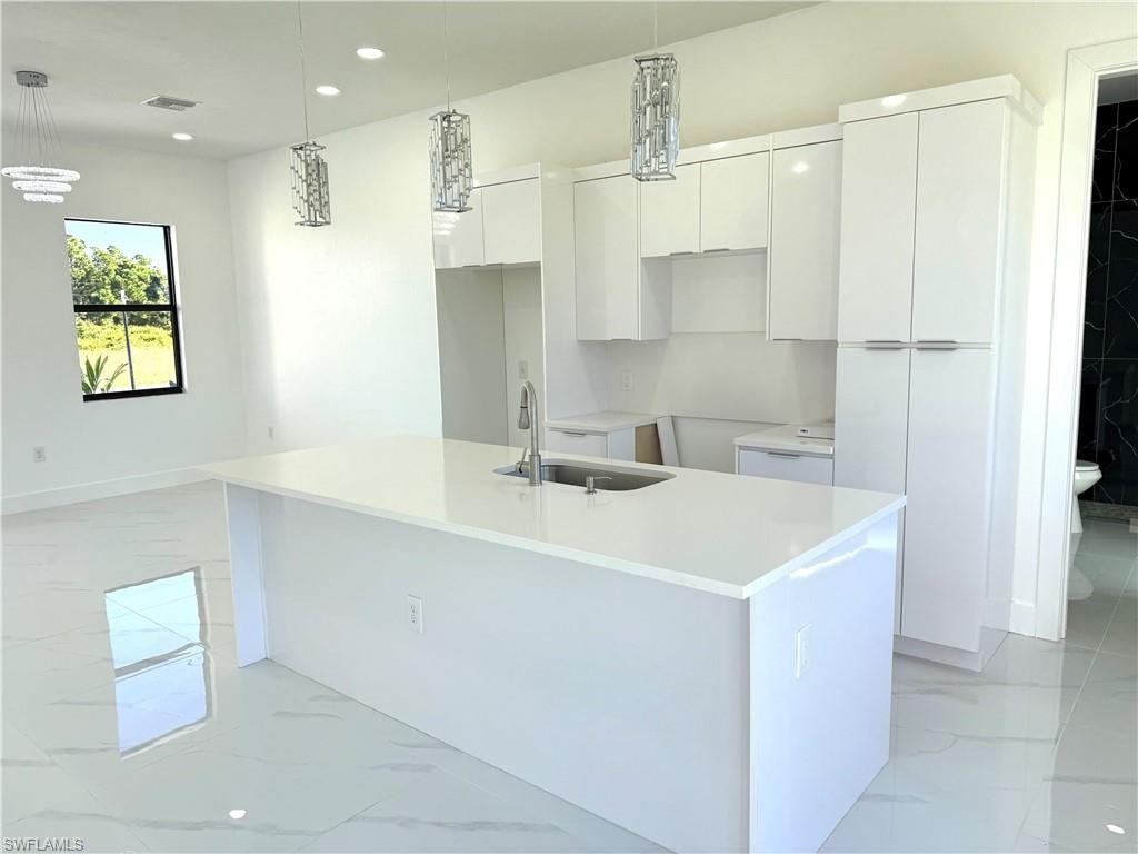 Kitchen with light marble finish floors, hanging light fixtures, stainless steel appliances, modern cabinets, and white cabinets