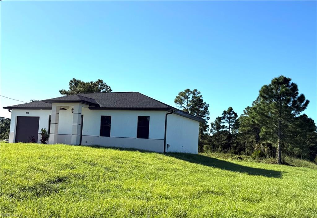 View of front of house featuring stucco siding, a garage, concrete driveway, and a front yard