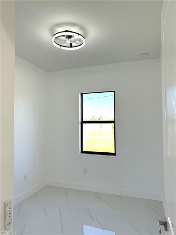 Empty room with baseboards and marble look tiles