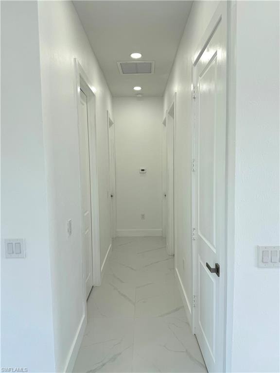 Kitchen featuring stainless steel appliances, light marble finish floors, decorative light fixtures, recessed lighting, and a center island with sink