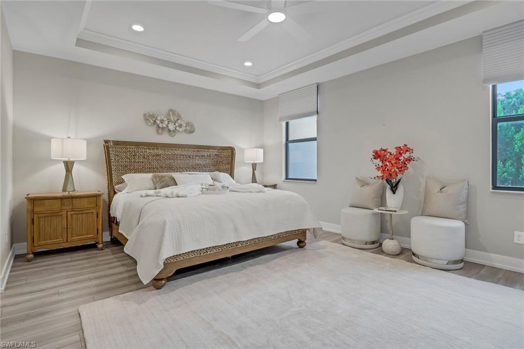 Bedroom with a tray ceiling, recessed lighting, light wood finished floors, ceiling fan, and crown molding