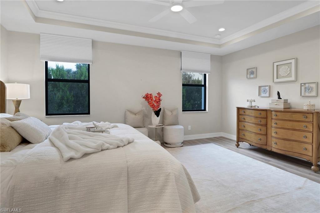 Bedroom featuring a tray ceiling, wood finished floors, recessed lighting, ceiling fan, and crown molding