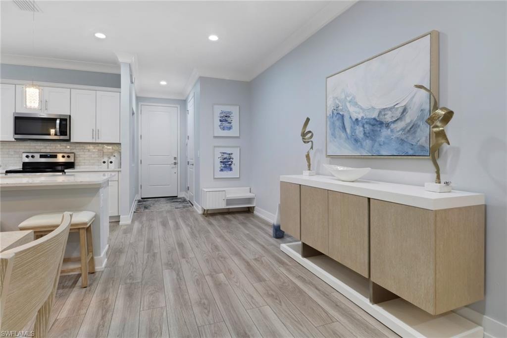 Kitchen featuring hanging light fixtures, crown molding, backsplash, stainless steel appliances, and recessed lighting
