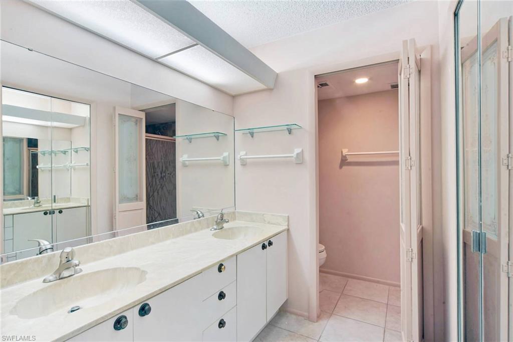 Primary suite bathroom with double sinks private water closet and walk in clothing closet