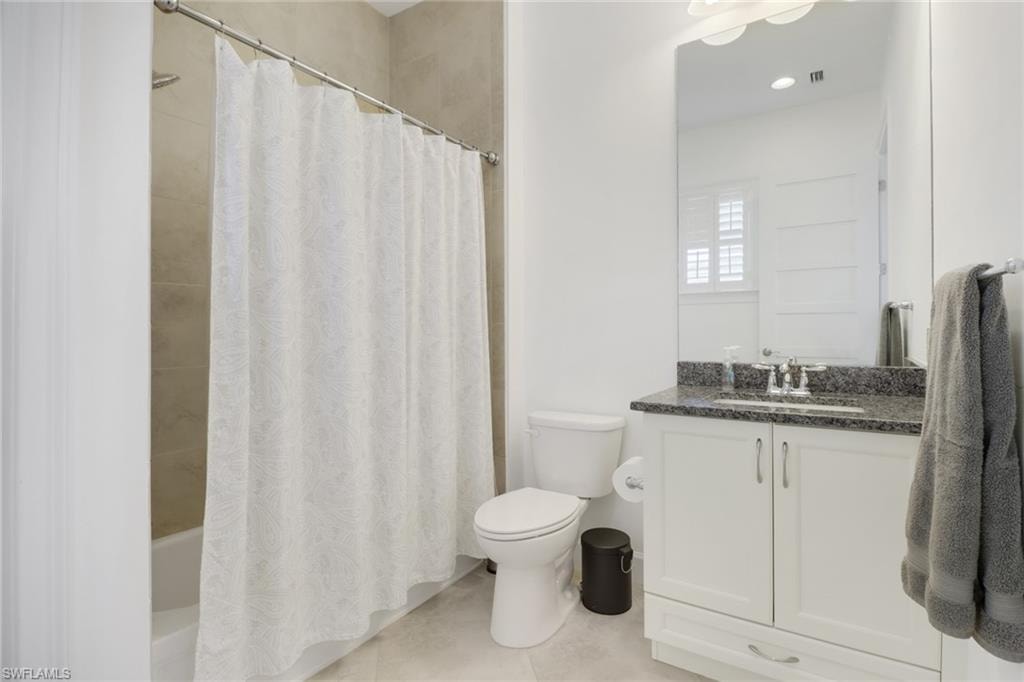 Full bathroom with vanity, toilet, tile patterned floors, and shower / tub combo with curtain