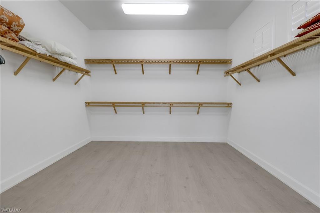 Walk in closet with light hardwood / wood-style flooring