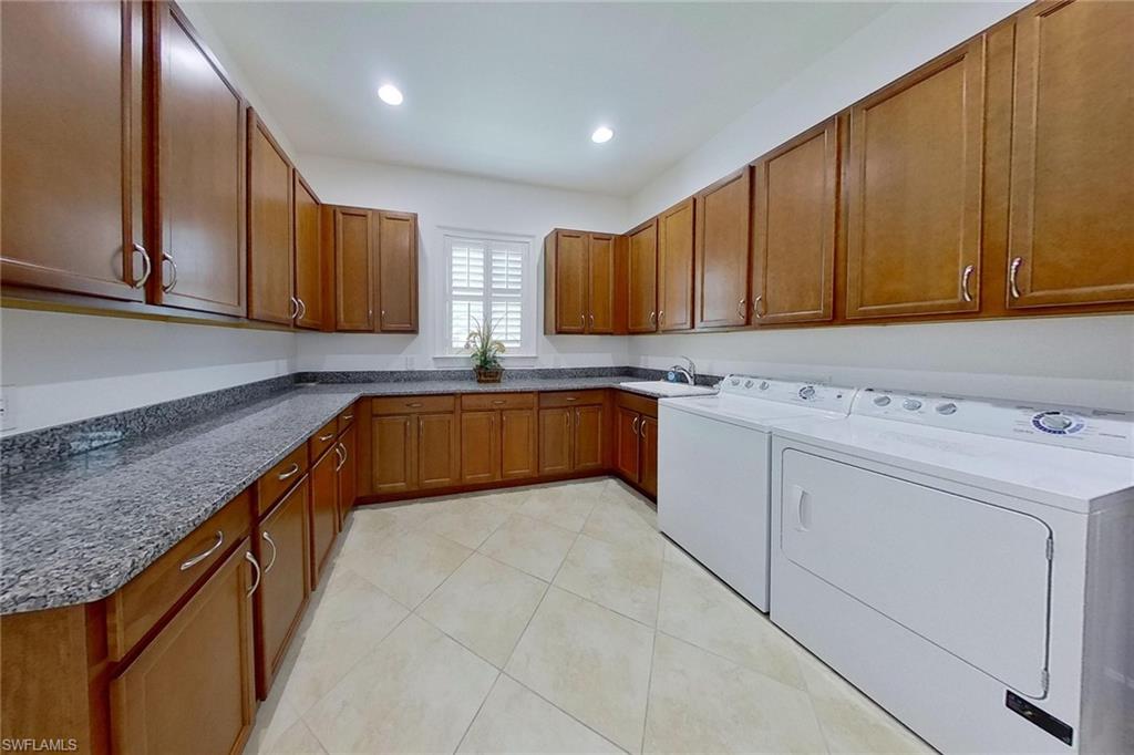 Laundry room with sink, light tile patterned flooring, independent washer and dryer, and cabinets