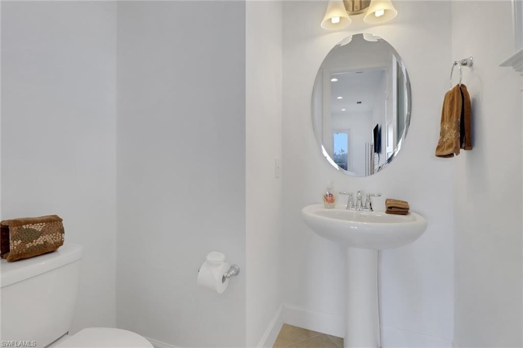 Bathroom featuring toilet, sink, and tile patterned flooring