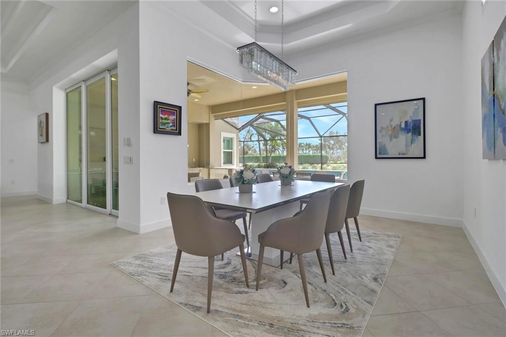 Dining area featuring ceiling fan, a raised ceiling, and light tile patterned floors