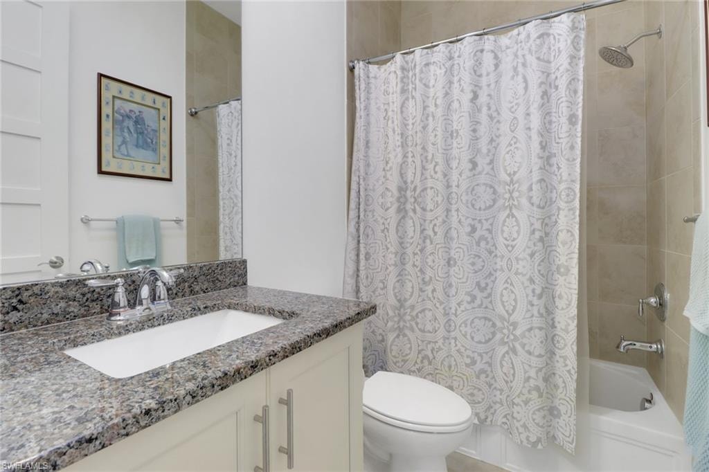 Full bathroom featuring vanity, shower / bath combination with curtain, and toilet