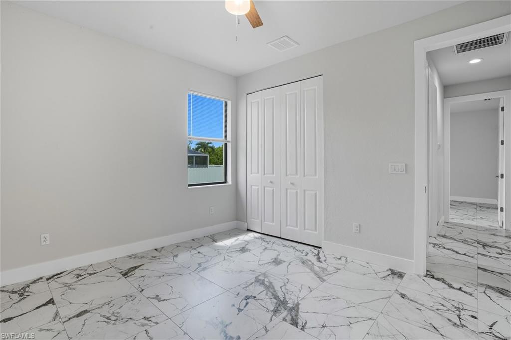 Unfurnished bedroom featuring light marble finish flooring, a closet, and a ceiling fan