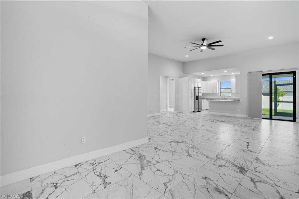 Unfurnished living room with light marble finish flooring, recessed lighting, and a ceiling fan
