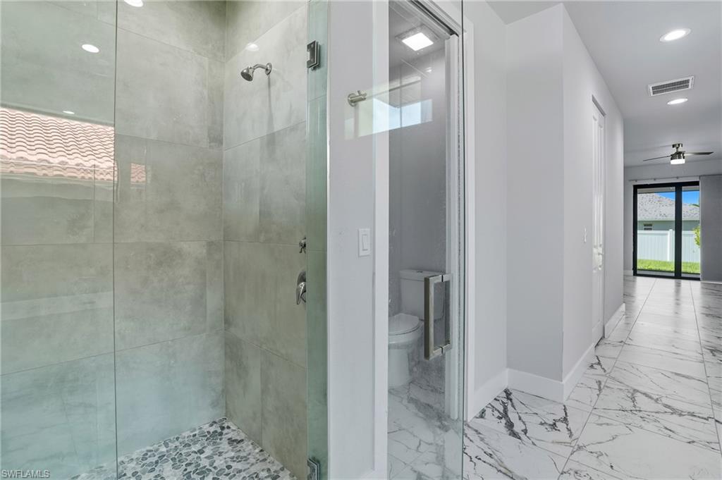 Full bathroom featuring a stall shower, marble look tiles, a ceiling fan, and recessed lighting