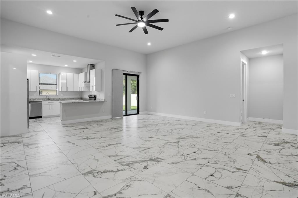 Unfurnished living room with light marble finish floors, healthy amount of natural light, recessed lighting, and ceiling fan
