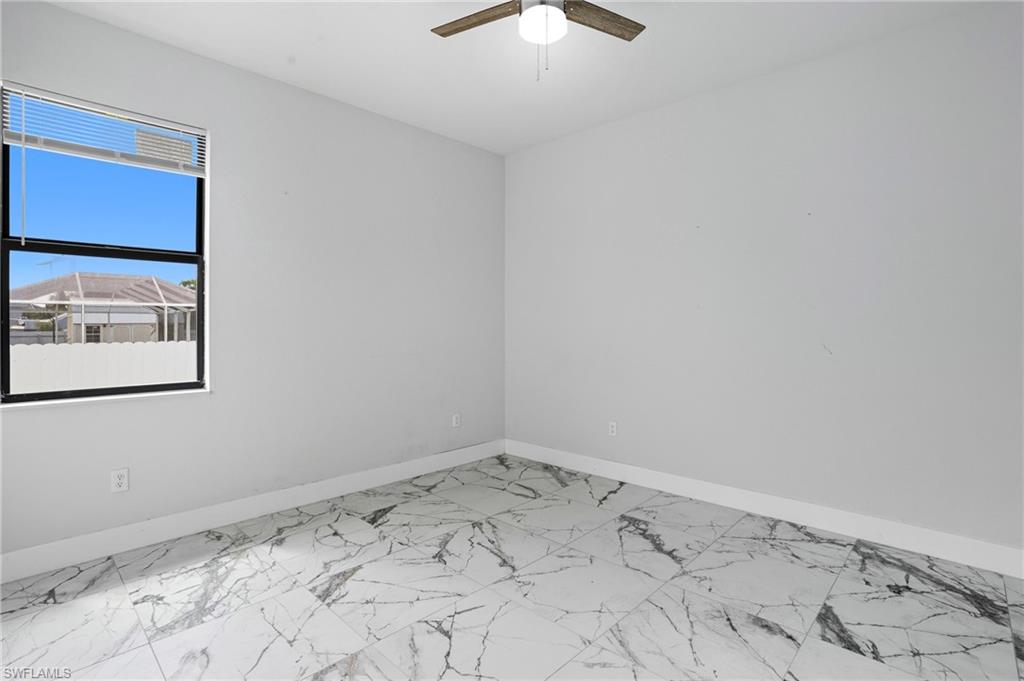 Unfurnished room featuring light marble finish floors and a ceiling fan