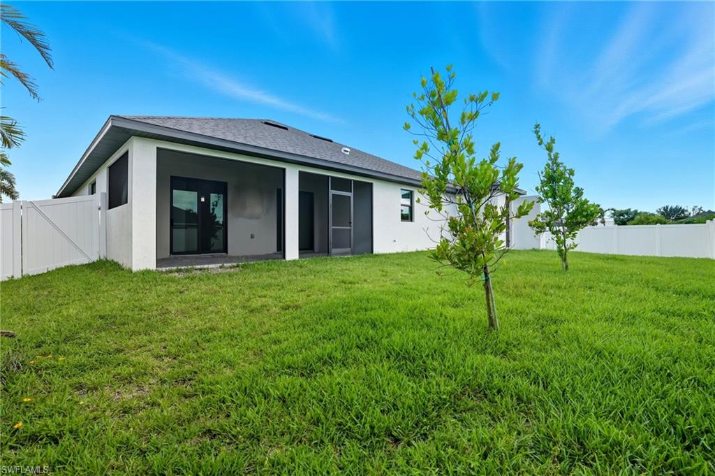 Rear view of property featuring stucco siding, a sunroom, and roof with shingles