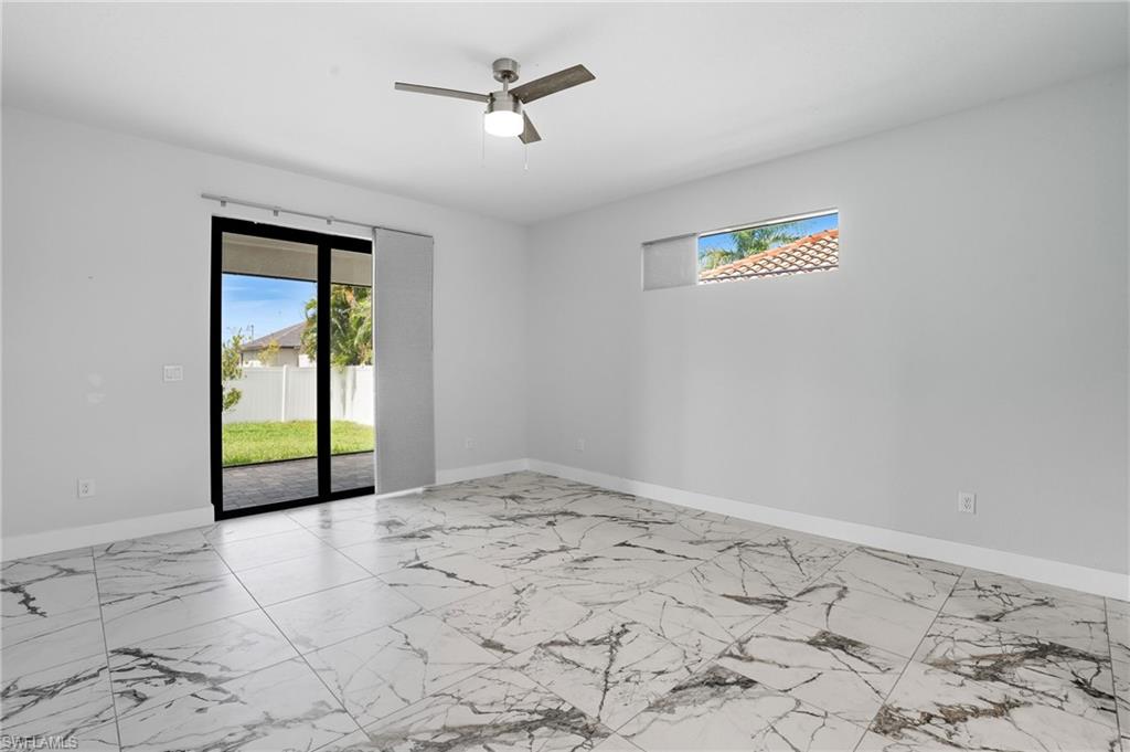 Spare room featuring light marble finish flooring, healthy amount of natural light, and a ceiling fan