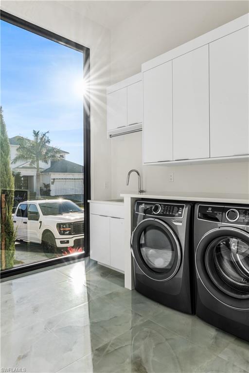 Laundry area with cabinet space and washer and clothes dryer