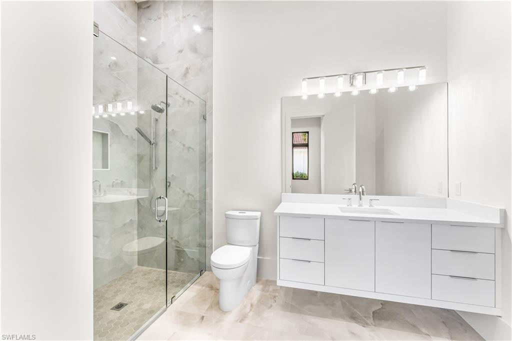 Bathroom featuring vanity and a marble finish shower
