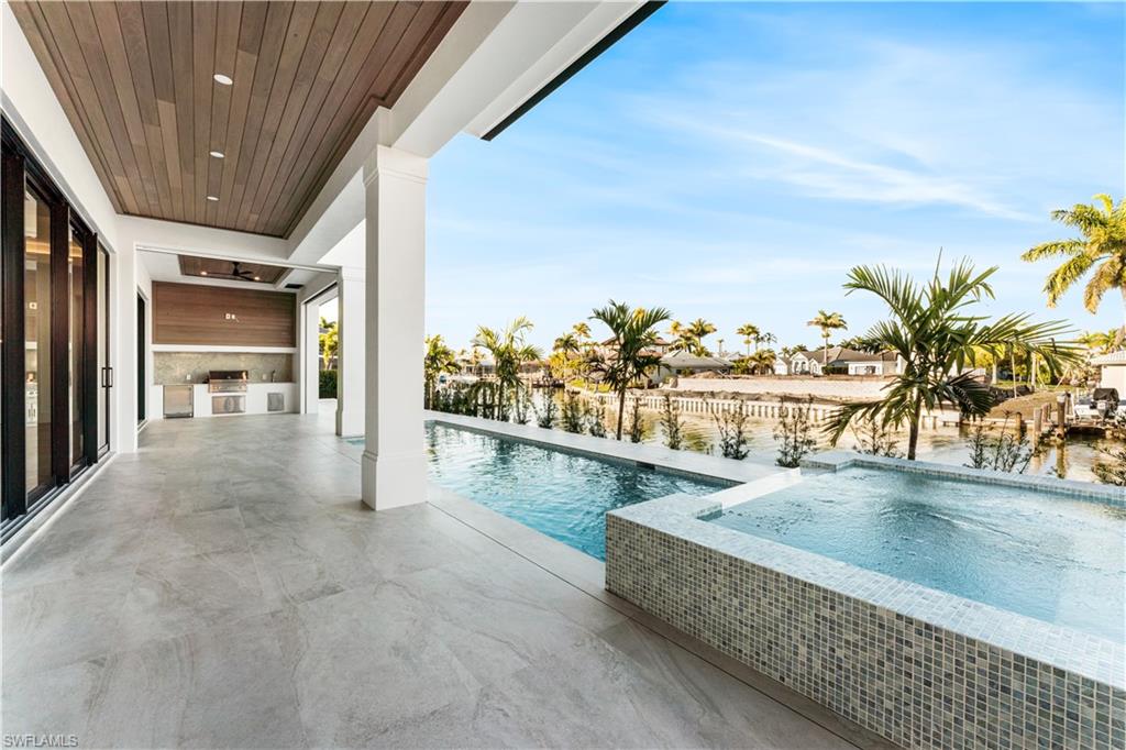 Outdoor pool with an in-ground hot tub, a patio, and an outdoor kitchen